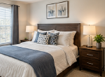 A cozy bedroom featuring a striped bedspread and a colorful fish painting on the wall.